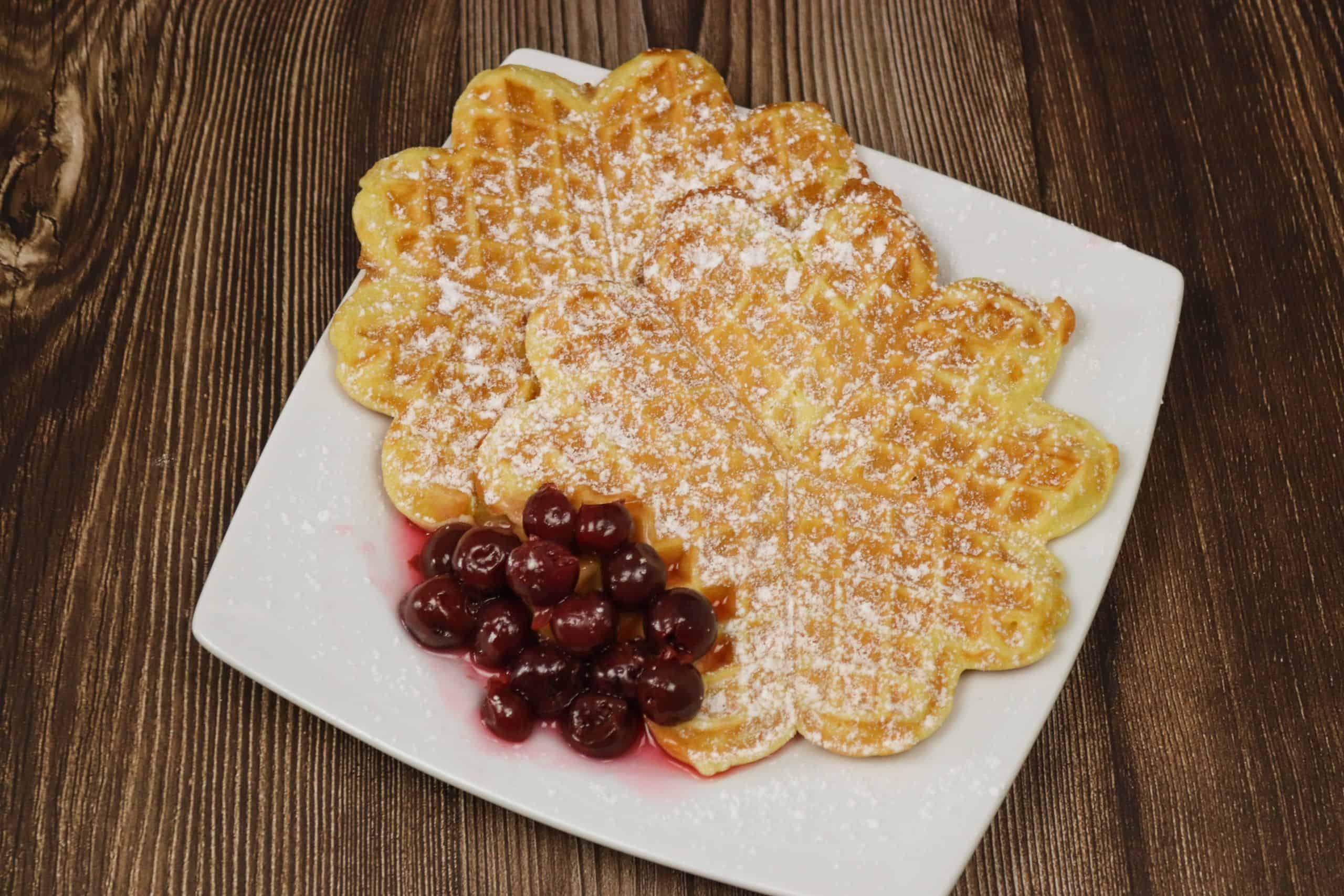 Leckere klassische Waffeln mir Kirschen auf einem Teller.